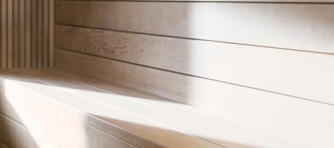 The seating bench inside a sauna is lit up by sunlight.