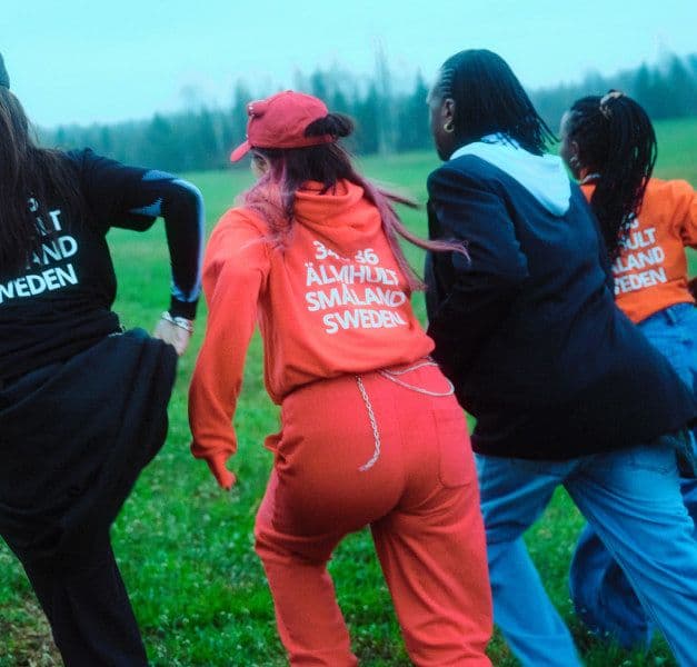 Four persons running on a green field from the camera.