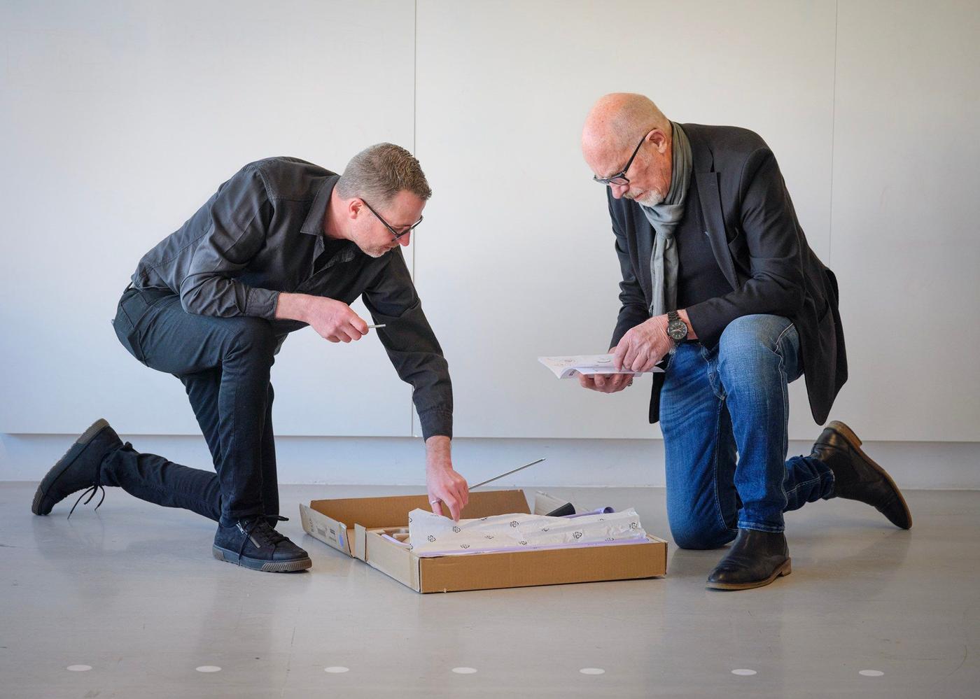 Two men kneeling over an IKEA flat pack.