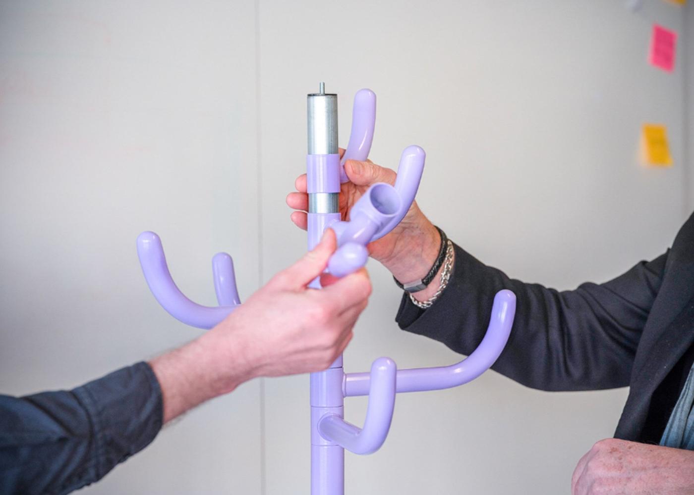 Two hands holding a purple coat hanger.