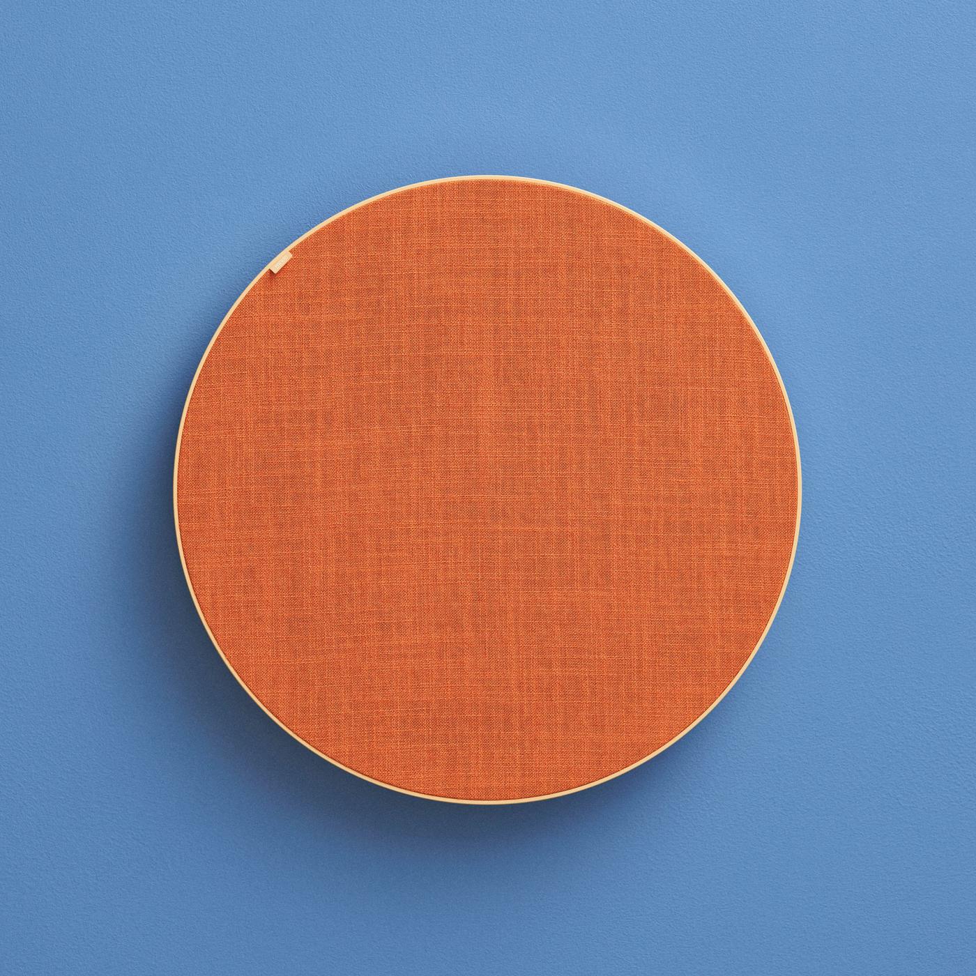 Large round orange SOLSKYDD speaker with a highly textured surface, hanging on the wall against a blue background.