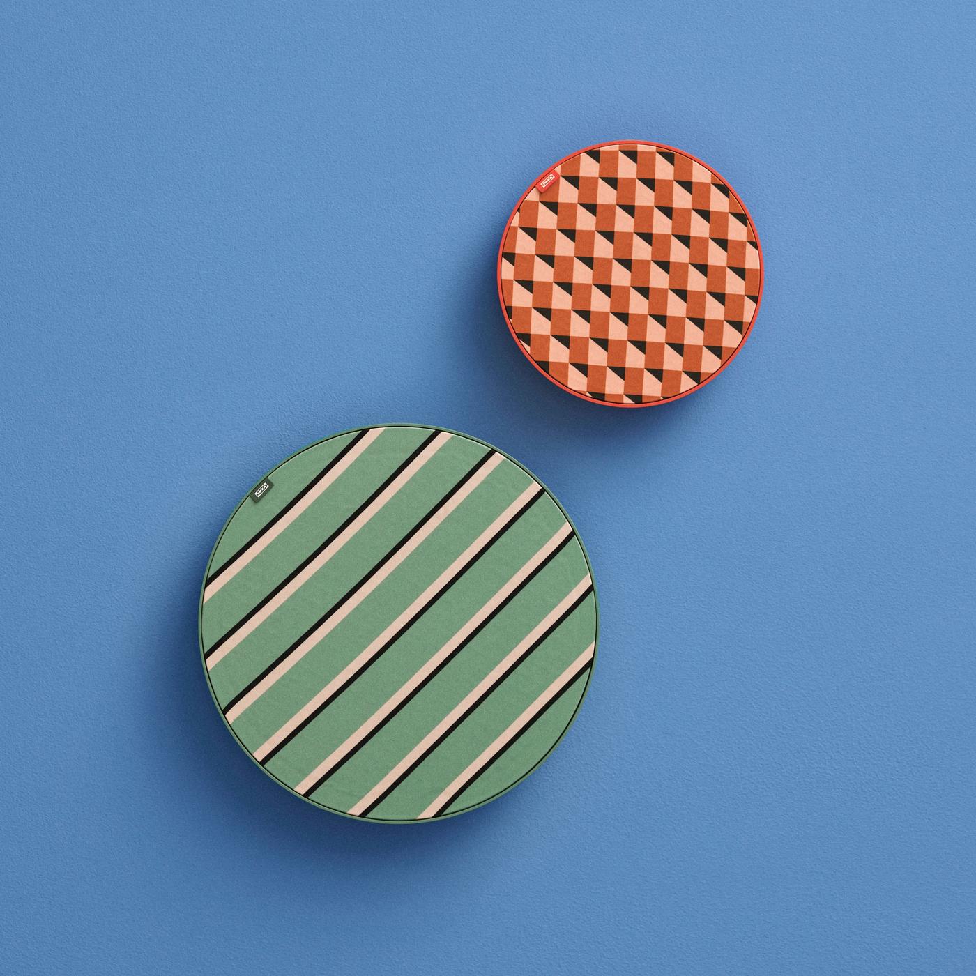 Patterned green and red round SOLSKYDD speakers hanging on a blue wall at different heights, with the green one noticeably larger and the red one positioned slightly above and to the right.