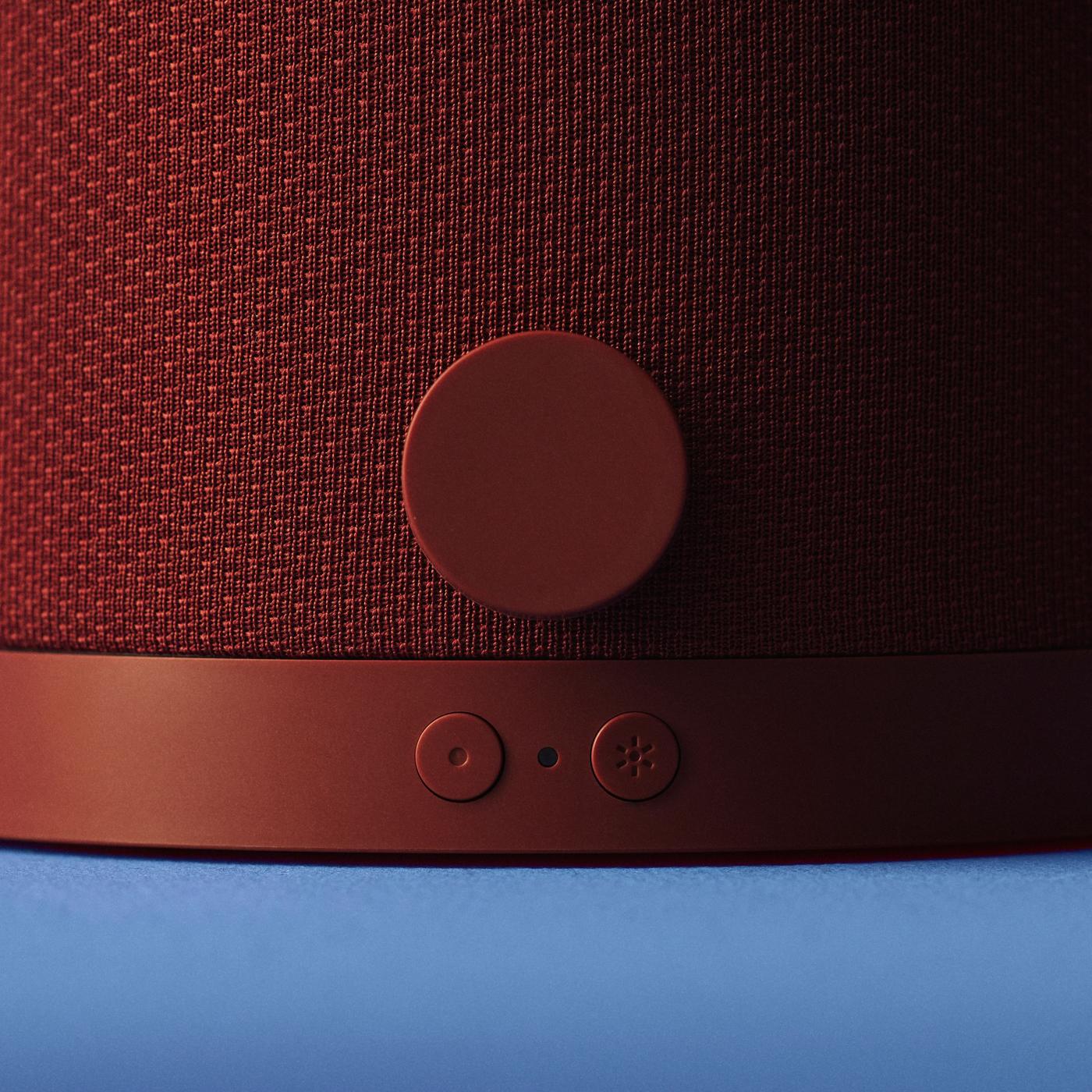 Close-up of red-brown mesh and button on a KULGLASS speaker.