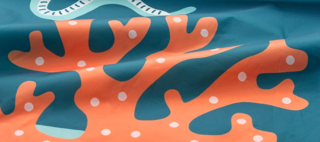 A piece of fabric printed with a blue background and orange and white seaweed.