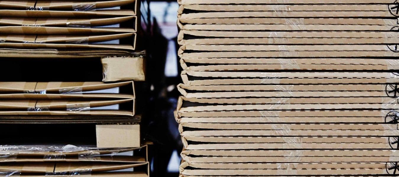 Pallets loaded with high stacks of cardboard flat-packs.