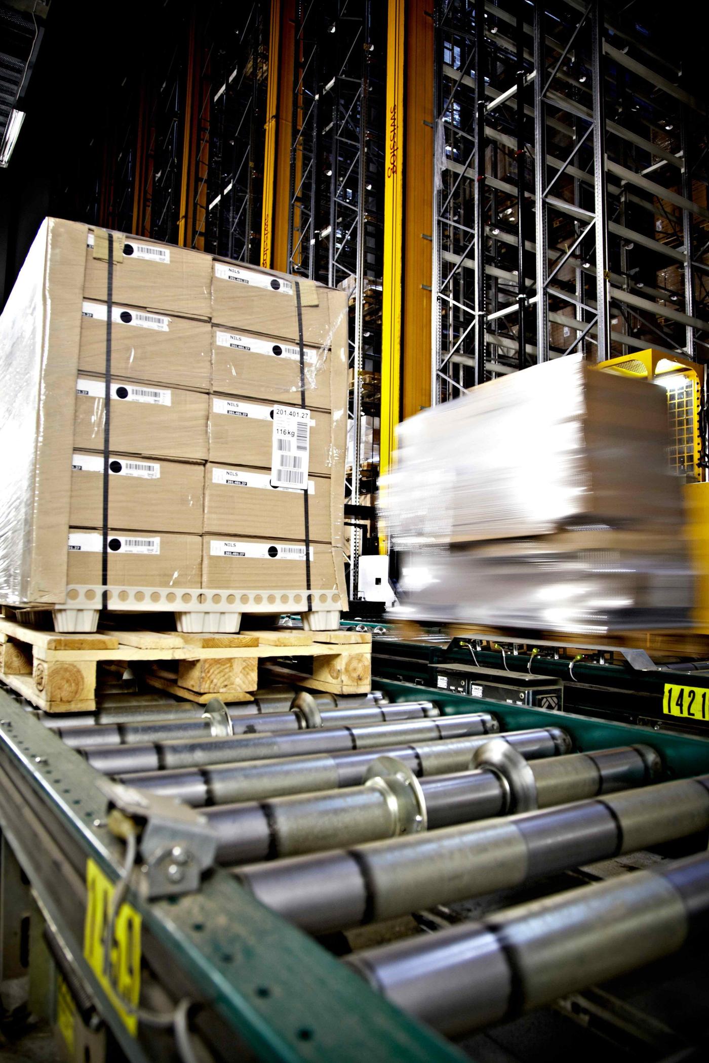 An industrial hall with parallel conveyor lines moving heavily loaded pallets.