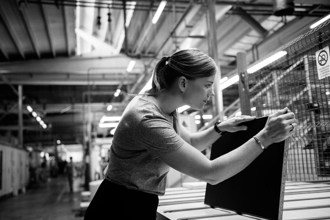A woman inspecting a piece of coated chipboard.