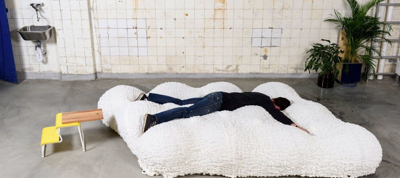 Man lying face down on a soft, white, bed-like futon.