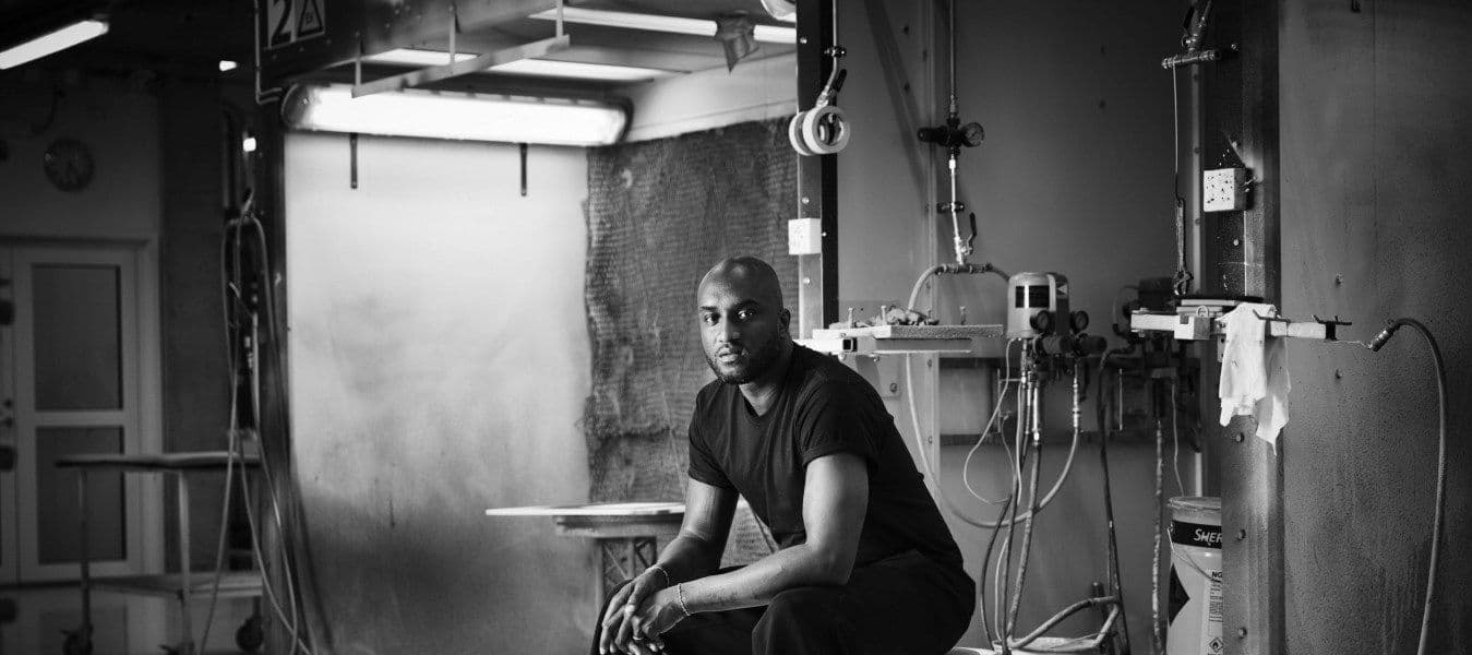 A black-and-white portrait of a man sitting in an industrial space.