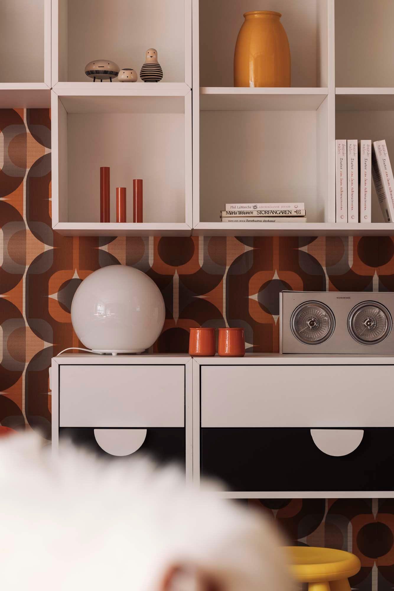 A white storage unit below a white shelving unit filled with retro objects.