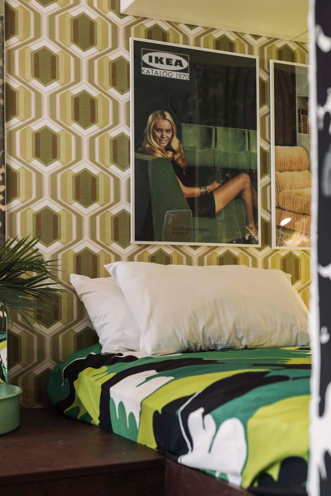 A bedroom with a retro IKEA catalogue poster on the wall above a bed dressed in bedding made from ÄNGSFIBBLA pre-cut fabric.