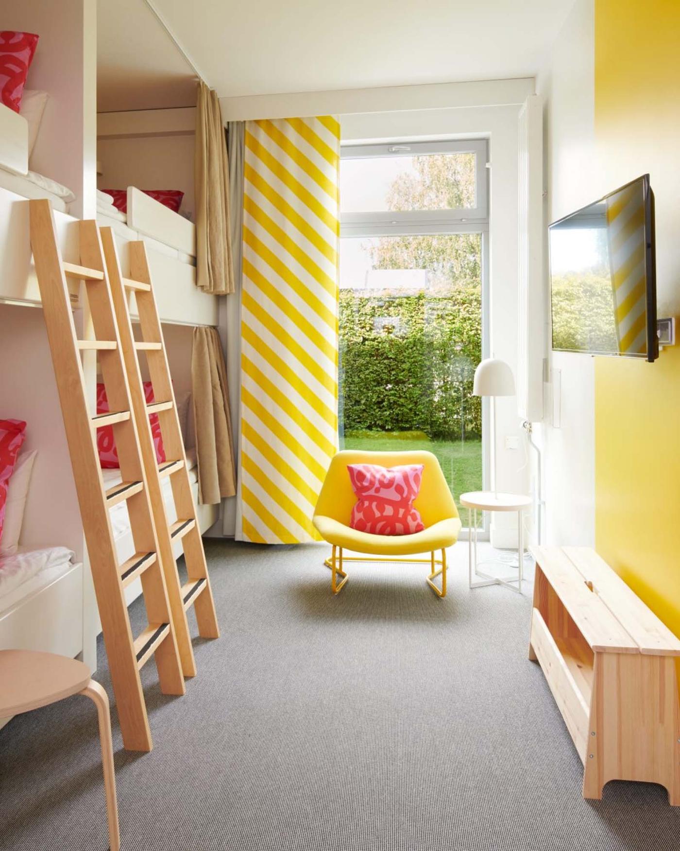 A modern day family room at the IKEA Hotell with happy colours, large windows and four bunk beds with ladders.