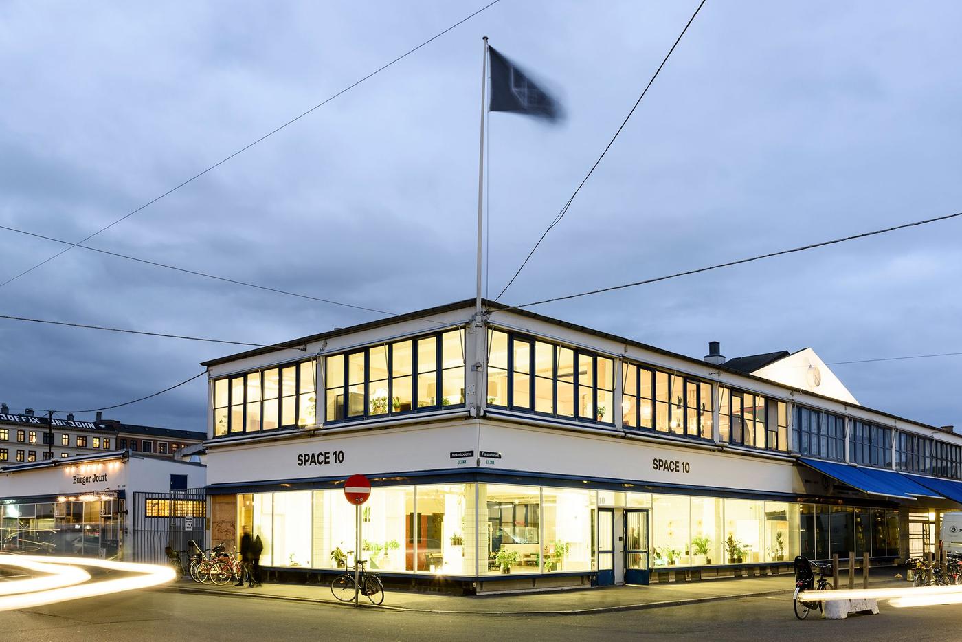 A two-storey, glass-wall building lit up from within and with signs reading 