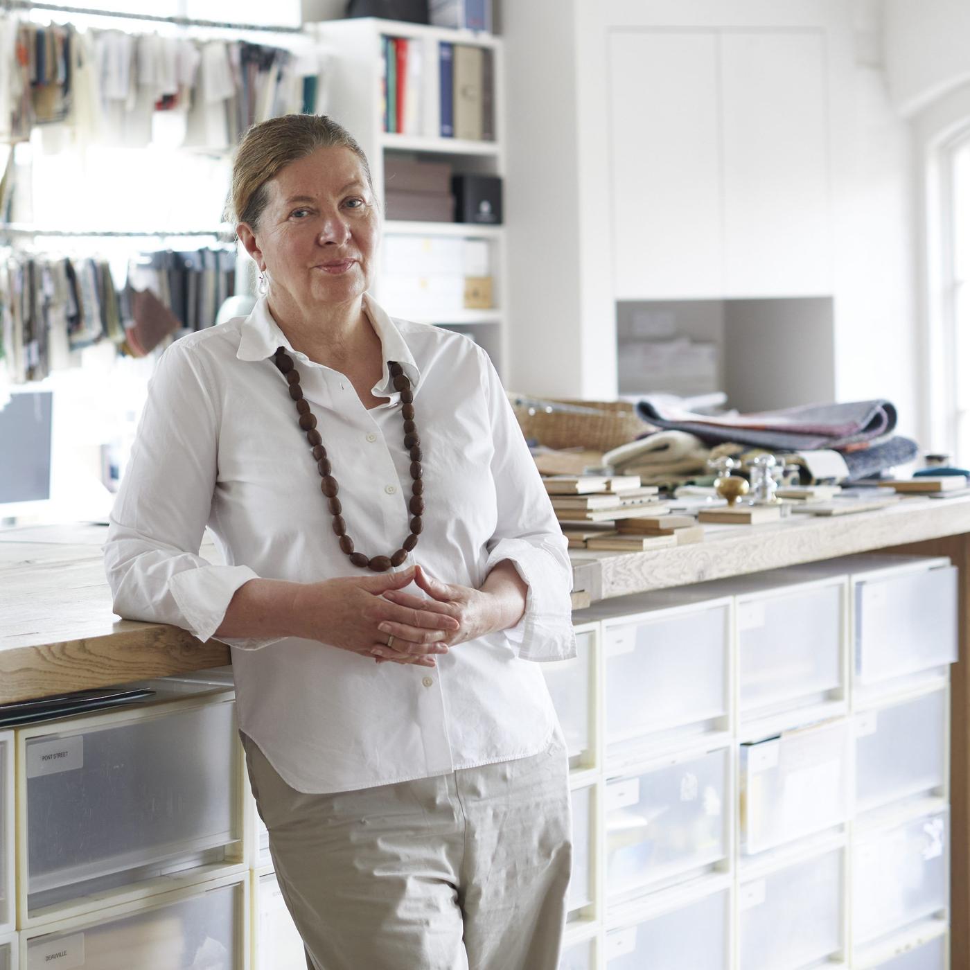 Ilse Crawford stands leaning back against a storage unit with hands clasped.