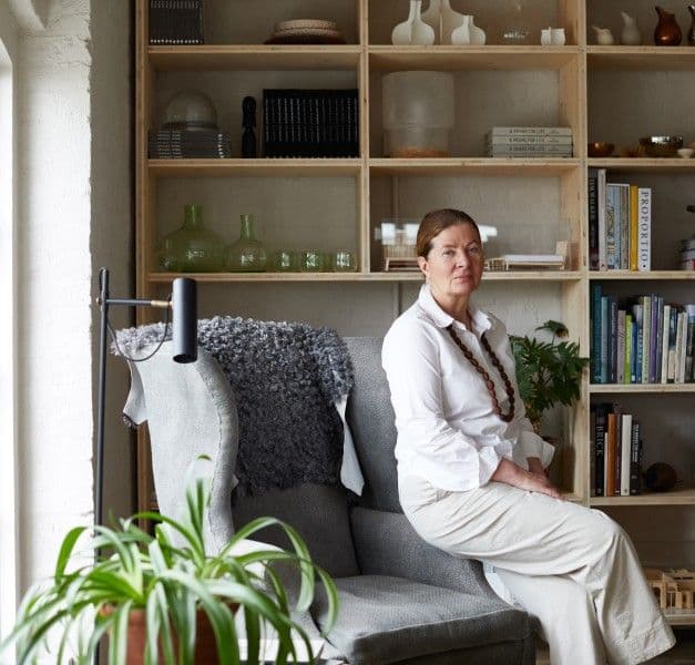 A woman sitting on a chair in front of a bookcase