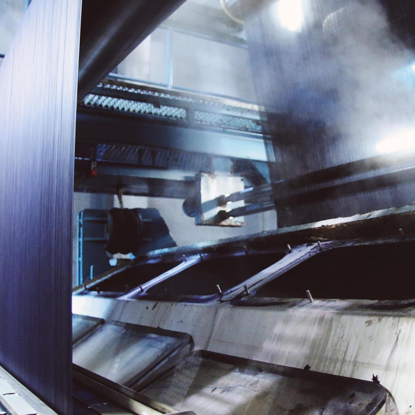 Steam rising up from a large machine with hundreds of fine blue threads running through it.