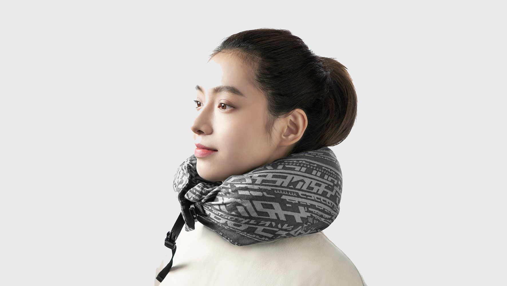 A woman in a white top wearing a grey patterned neck cushion.