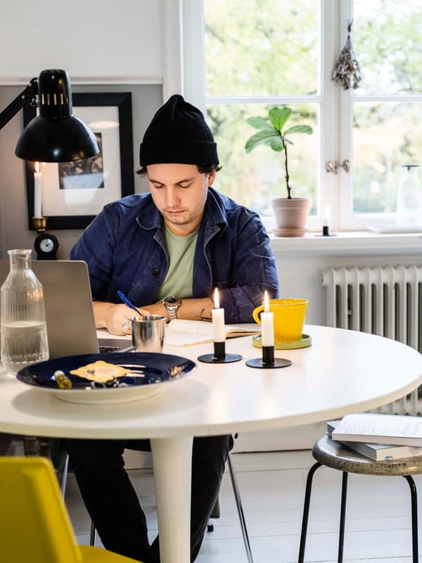 Linus sits and studies at a round, white dining table.