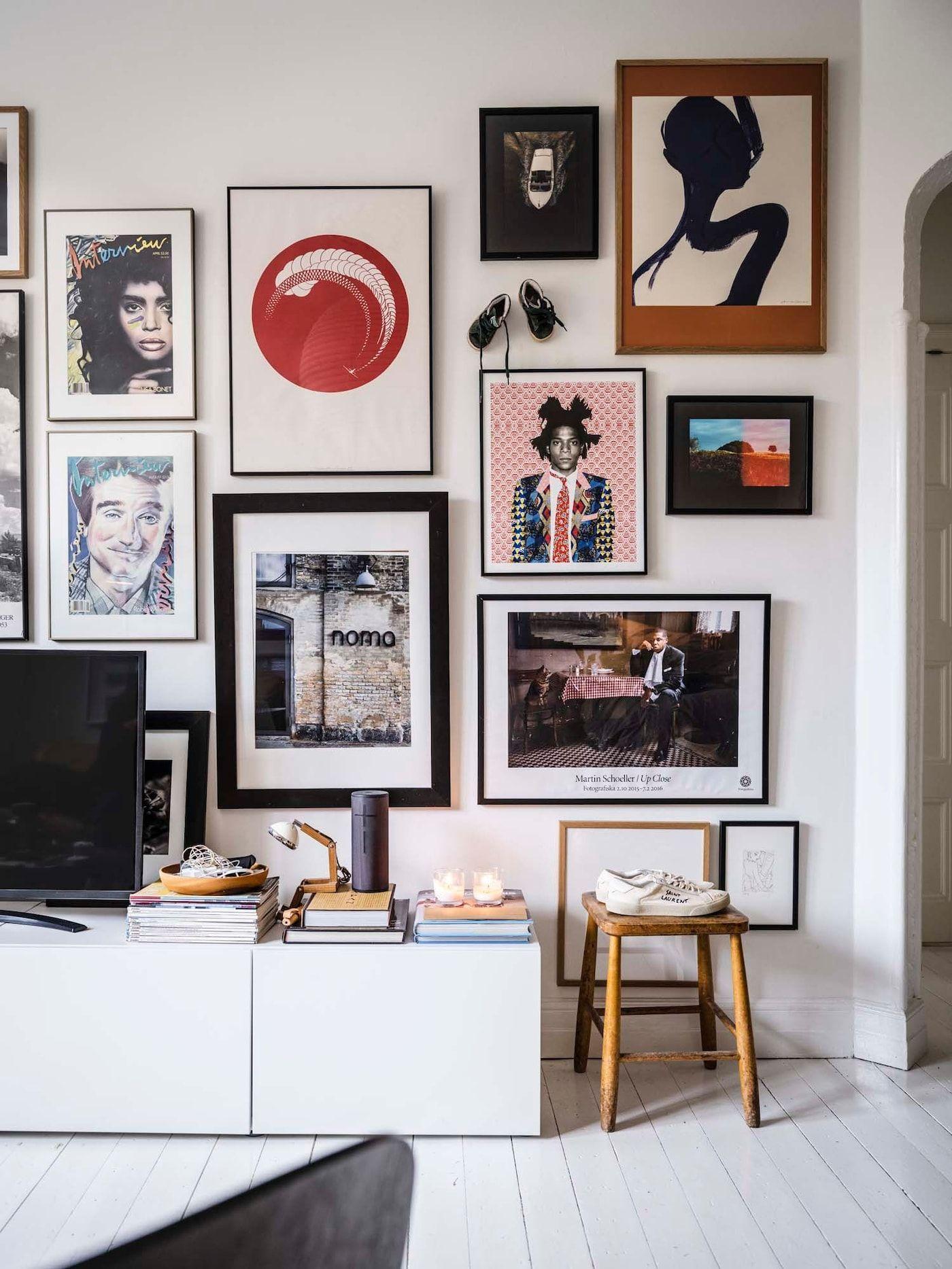 A gallery wall of photos and posters above a TV bench.