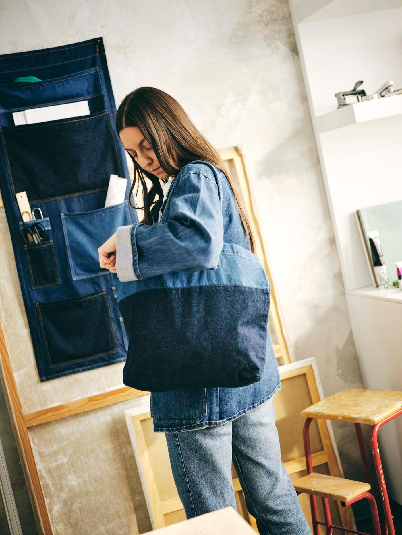 A woman looks into her denim bag. There is a denim organiser on the wall.