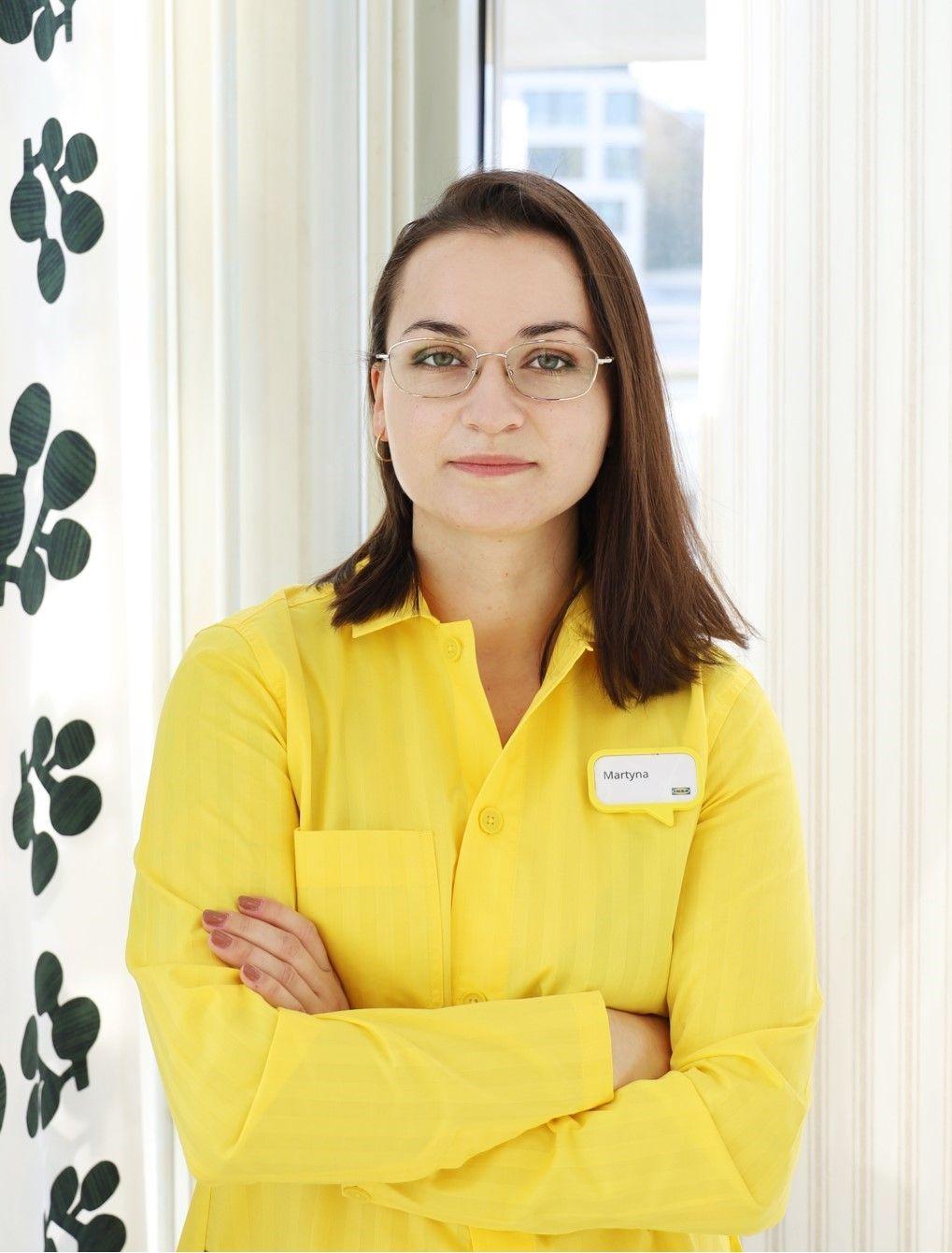 A woman in a yellow shirt standing with her arms crossed.