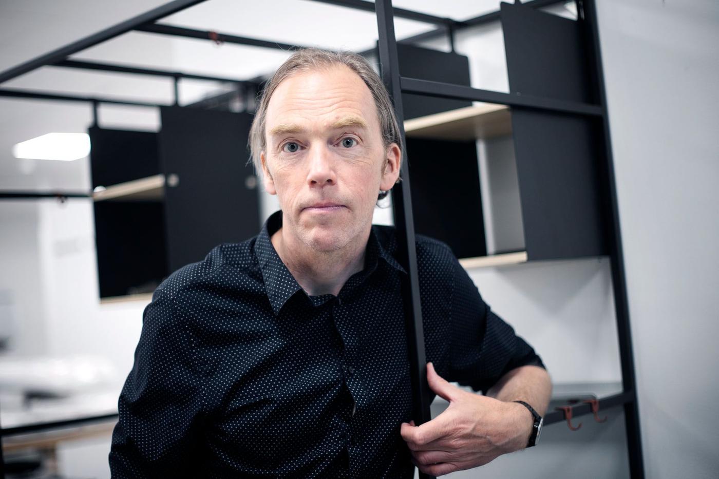 A man in a black shirt with white dots standing in a kitchen that's being assembled.