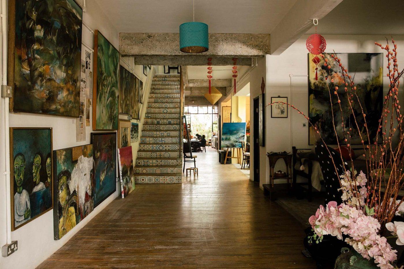 A large entryway with wooden floors and paintings on the walls, with a staircase in the background.