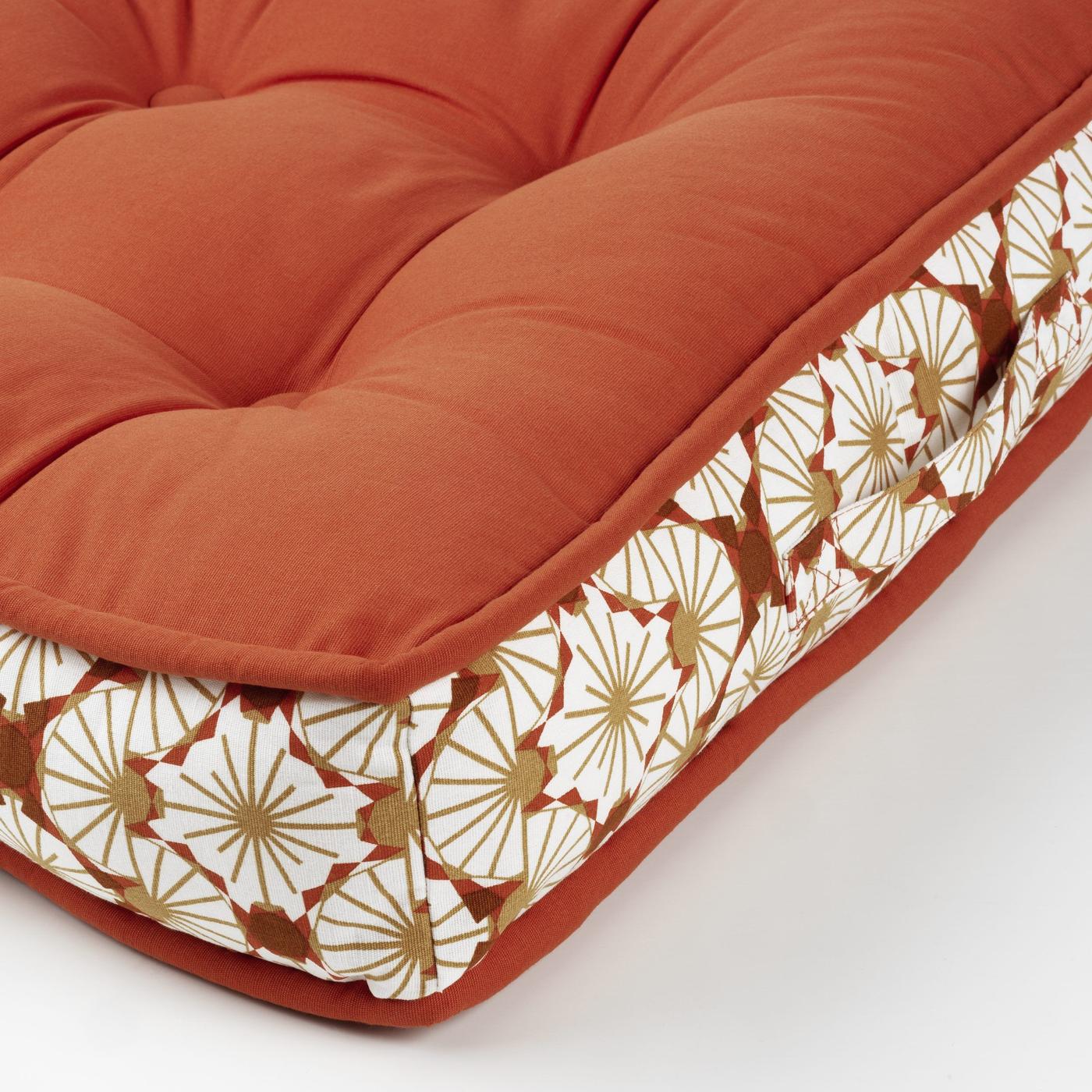 The angle of a sofa cushion in brick red and white flowers with beige details.