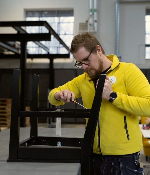 An IKEA co-worker using a screw driver on an IKEA chair.