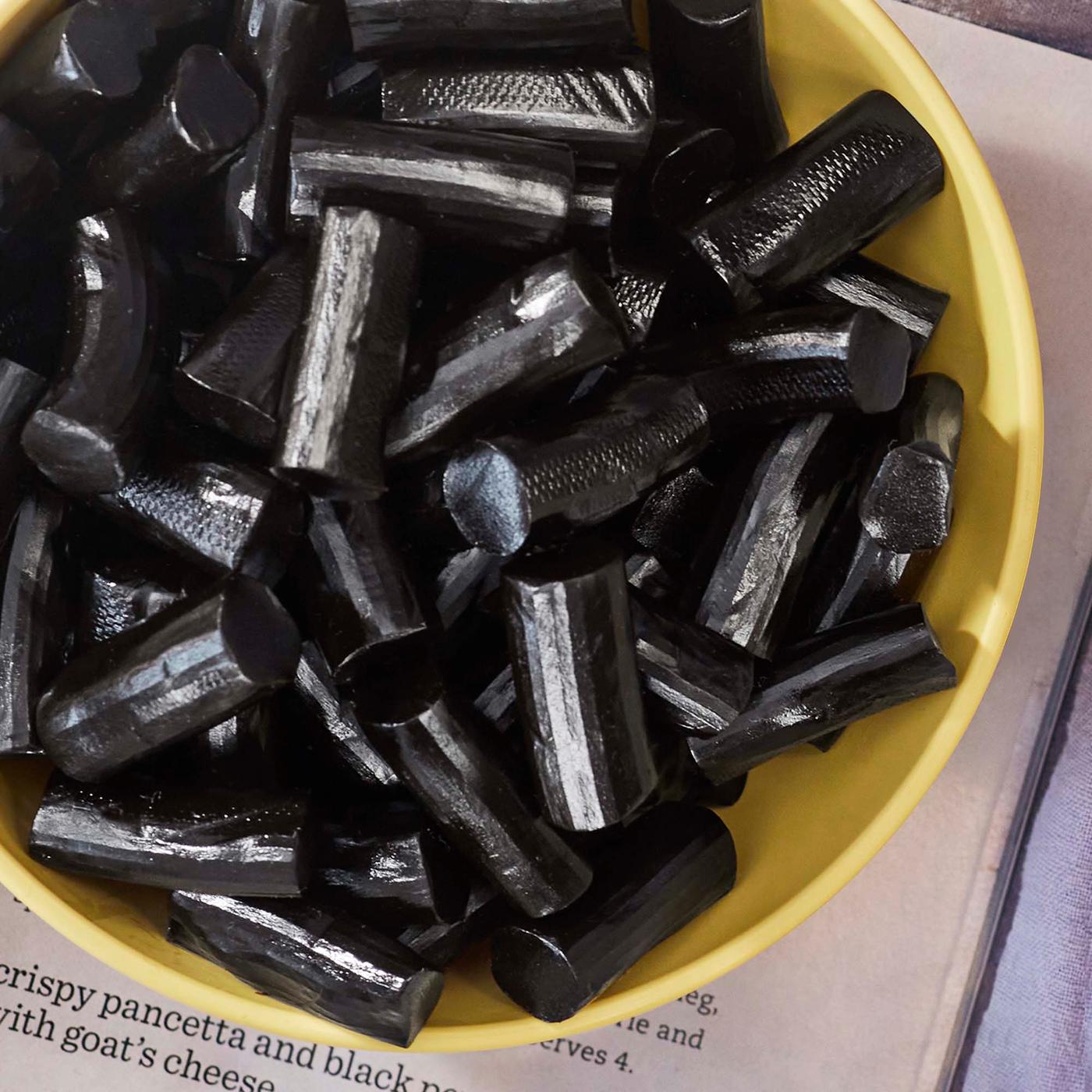 Licorice in a yellow bowl, placed on a page of text.