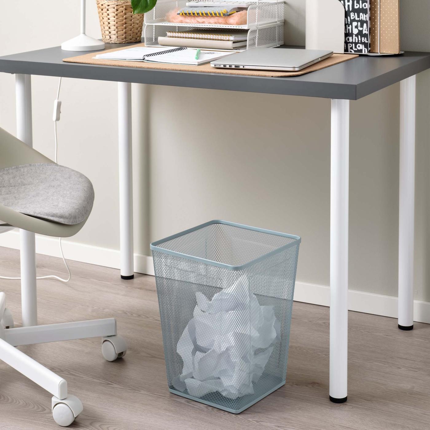 A light blue waste basket under a desk.