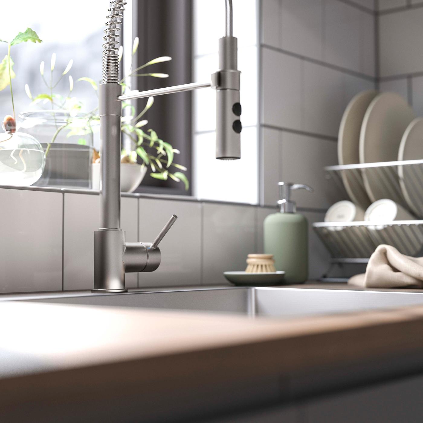 A close-up of the VIMMERN modern tap in stainless steel in a white and wood kitchen.