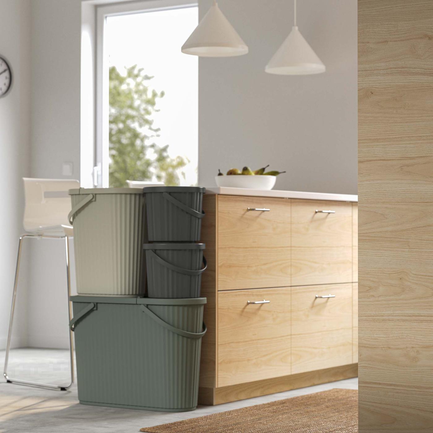 Three DAMMÄNG recycling containers are stacked against a kitchen island.