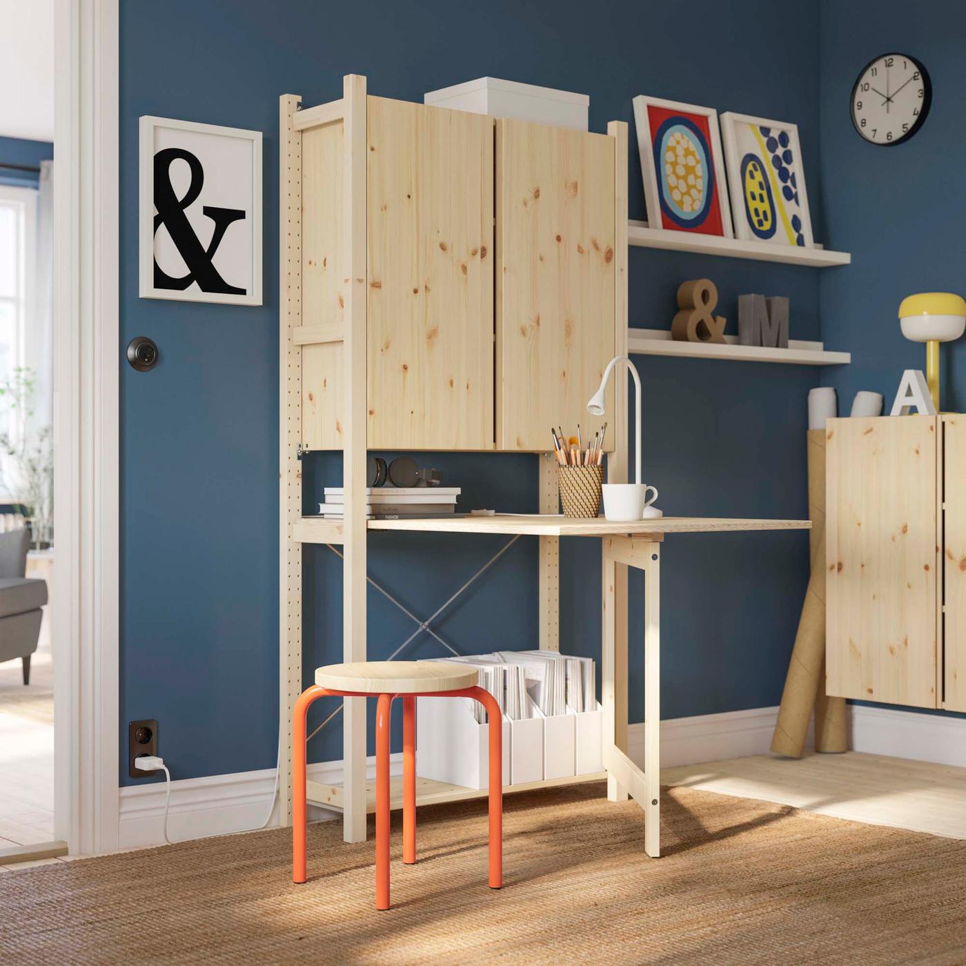 A room with wooden IVAR shelves and a desk.
