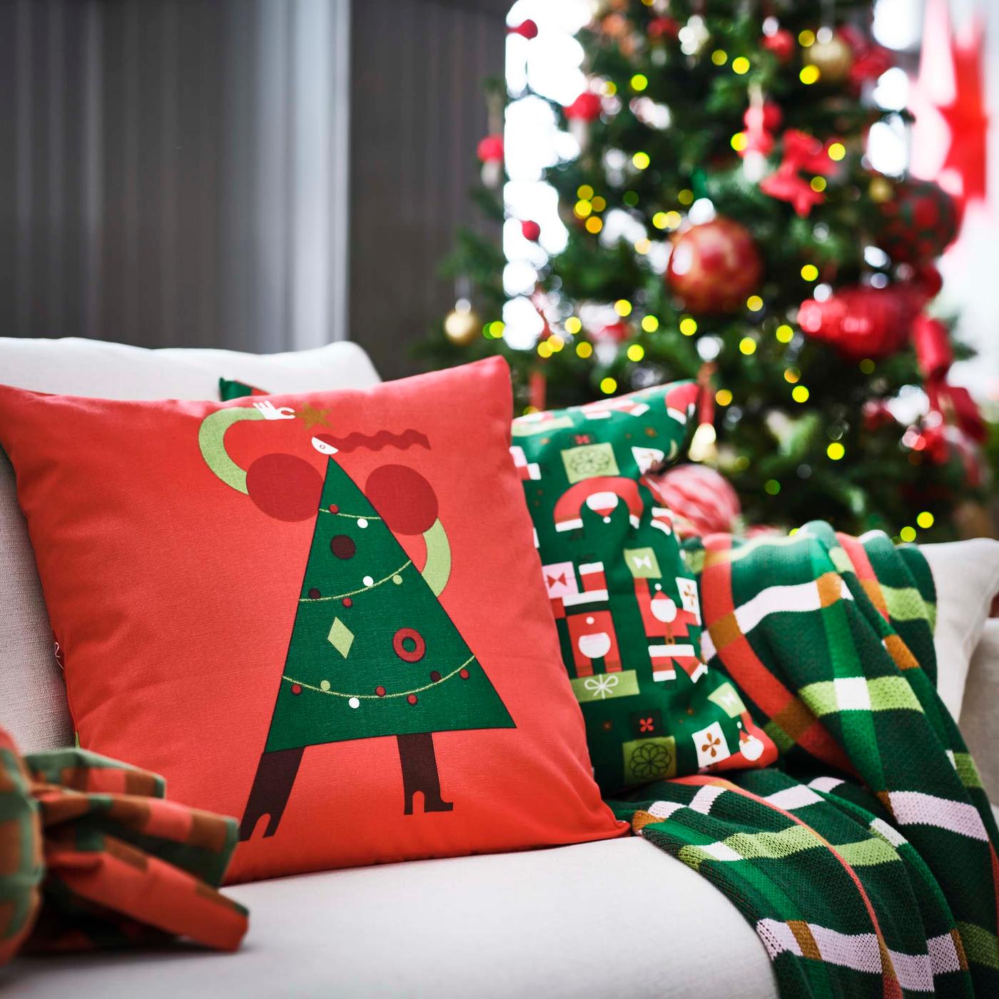 Bright red and green cushions with a Christmas-themed motif on a sofa in a living room.