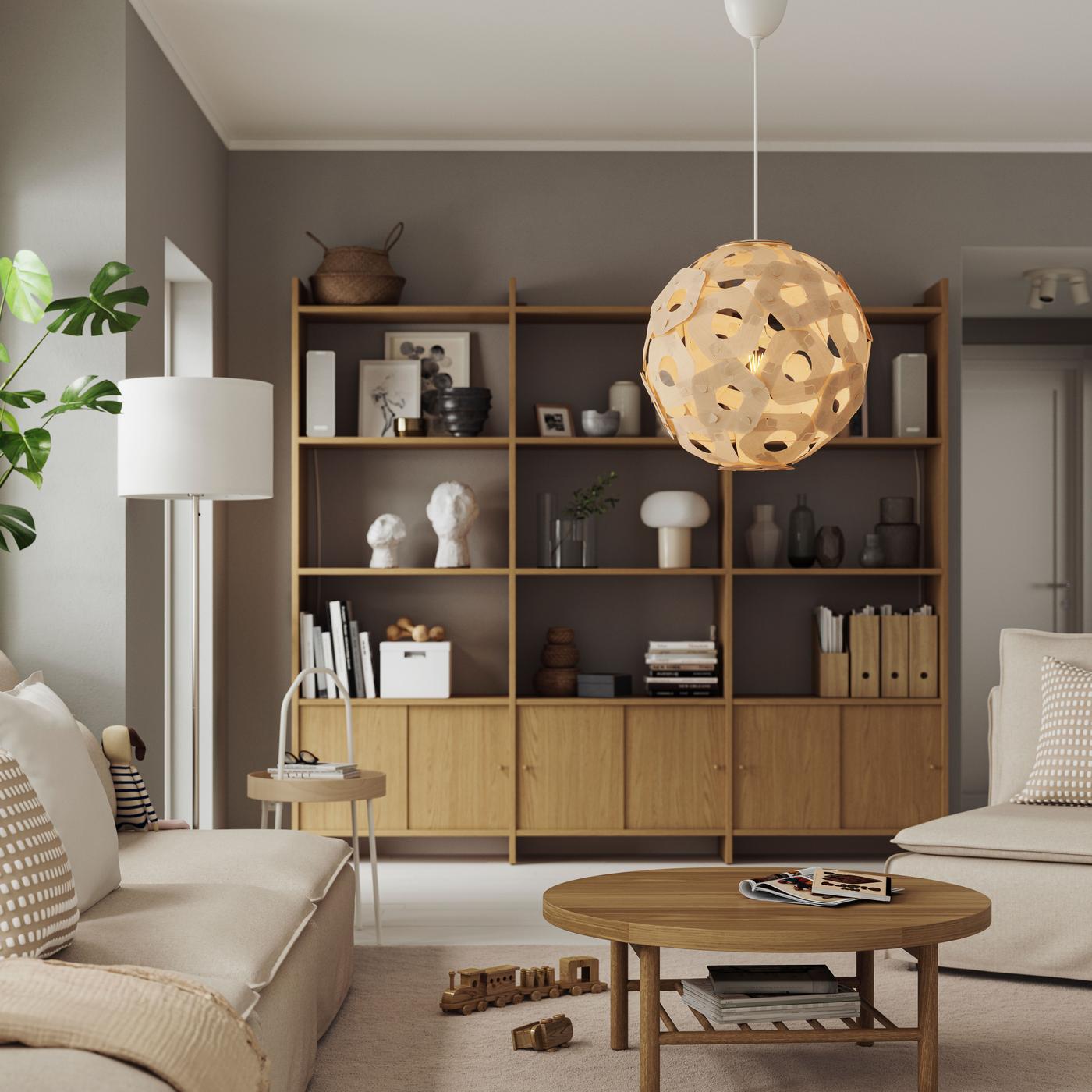 A wooden pendant lamp hanging over a dining table in a modern, open-layout living space.