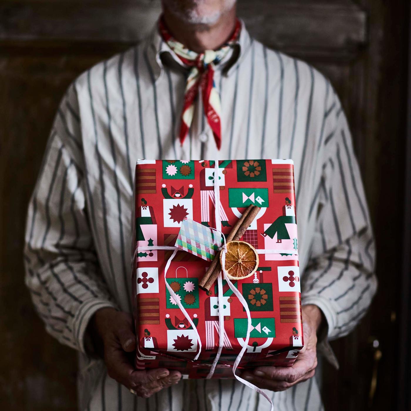 A close-up of a person holding a Christmas present wrapped in vibrant paper. with festive motifs.