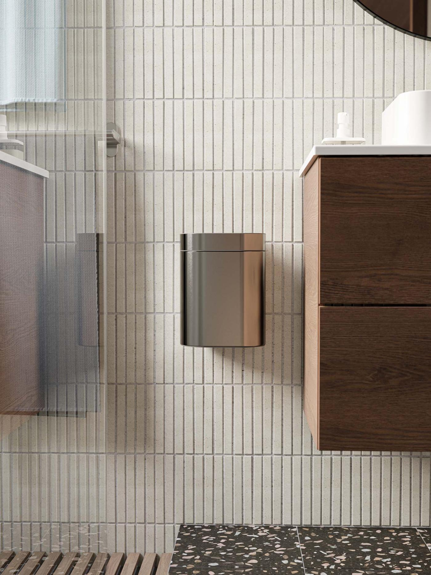 A small wall-hung BROGRUND bin next to a washbasin.