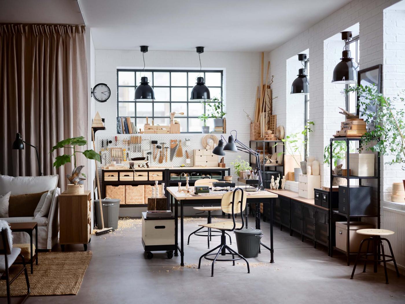 An industrial style work area, with bins in the corner and under the desk, and wood scraps on the floor.