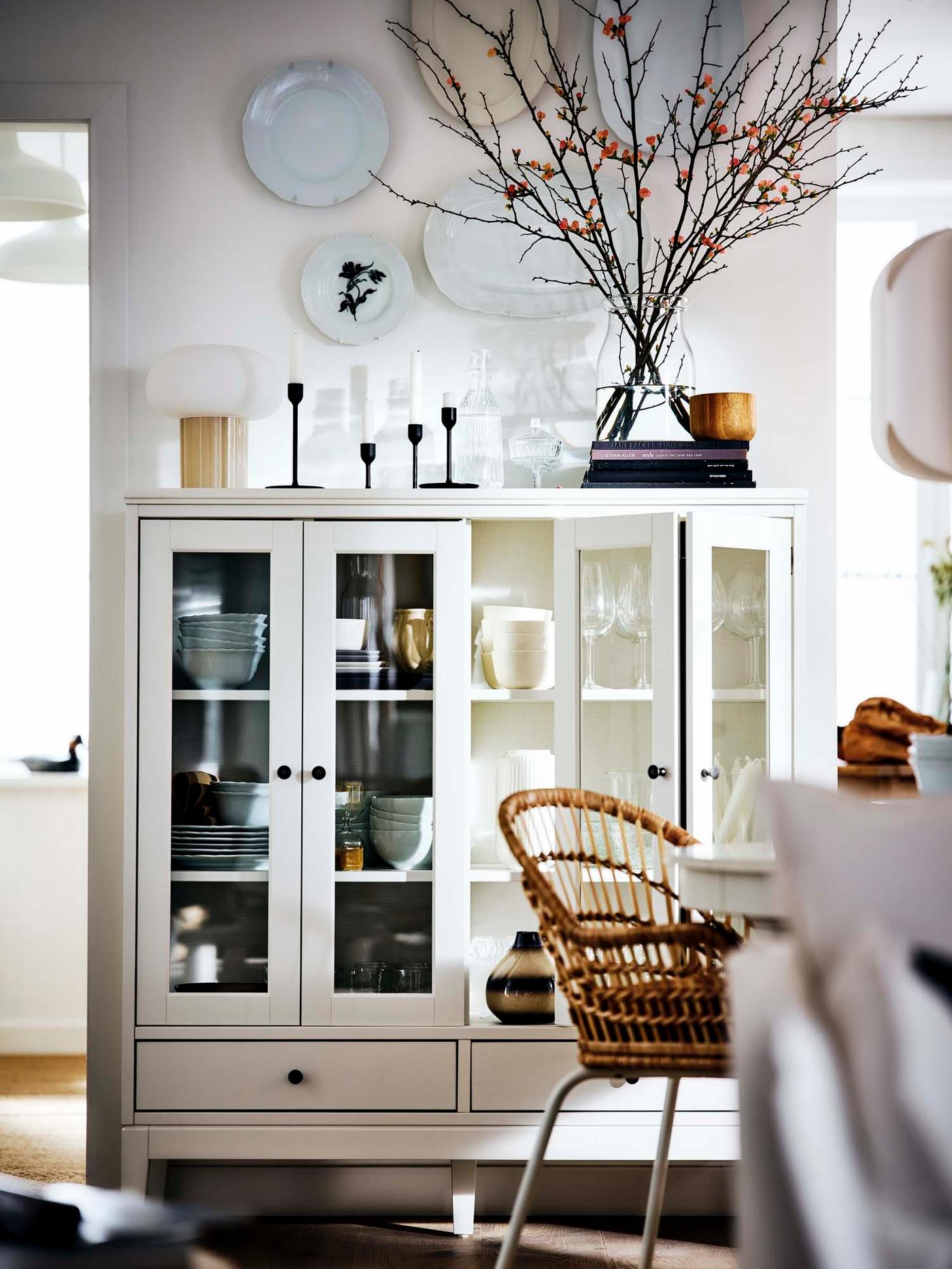 A classic white cabinet with bi-folded glass doors filled with porcelain.