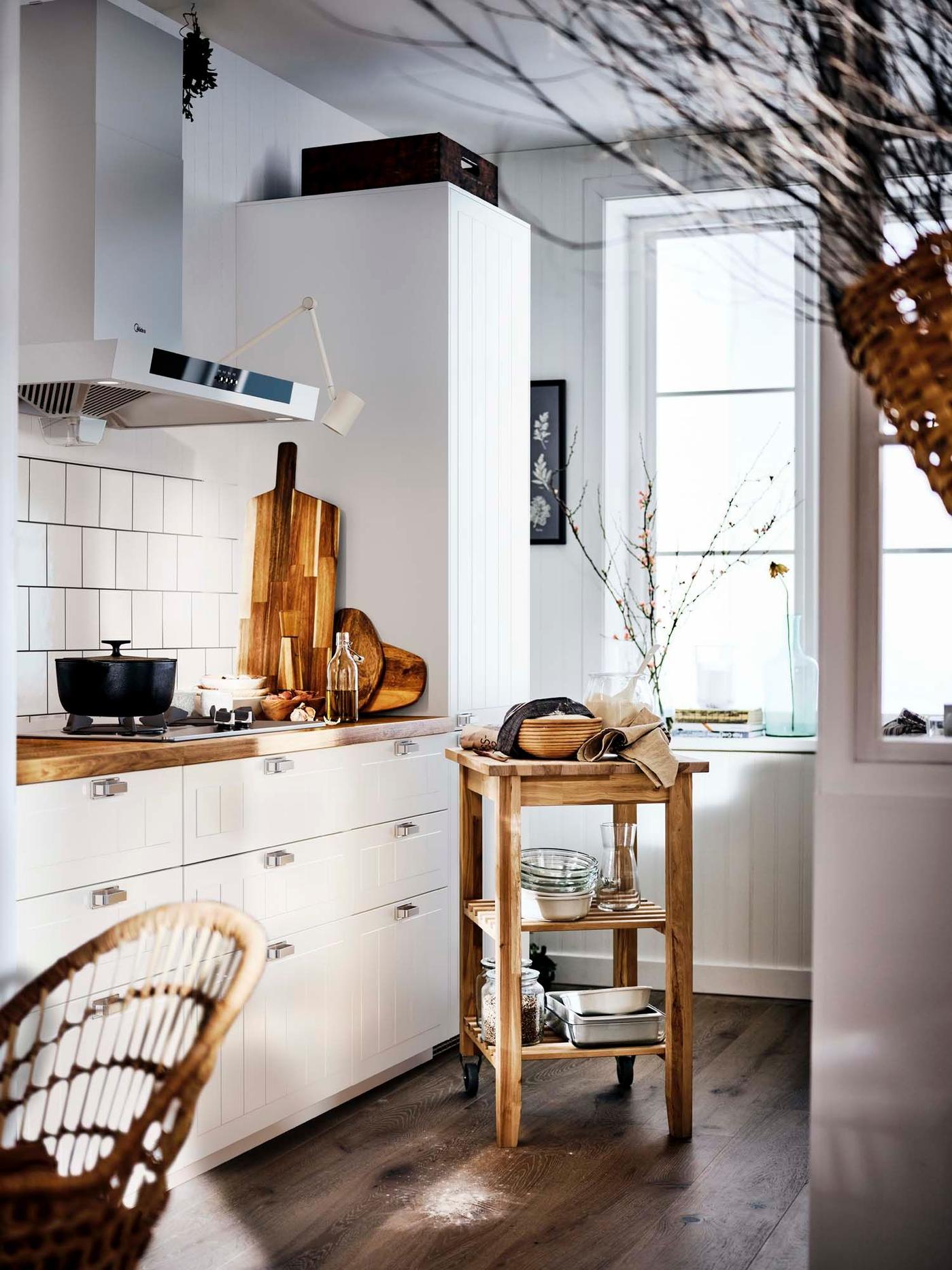 A light-filled traditional white STENSUND kitchen with a wooden worktop, wooden floor, and a wooden storage unit..