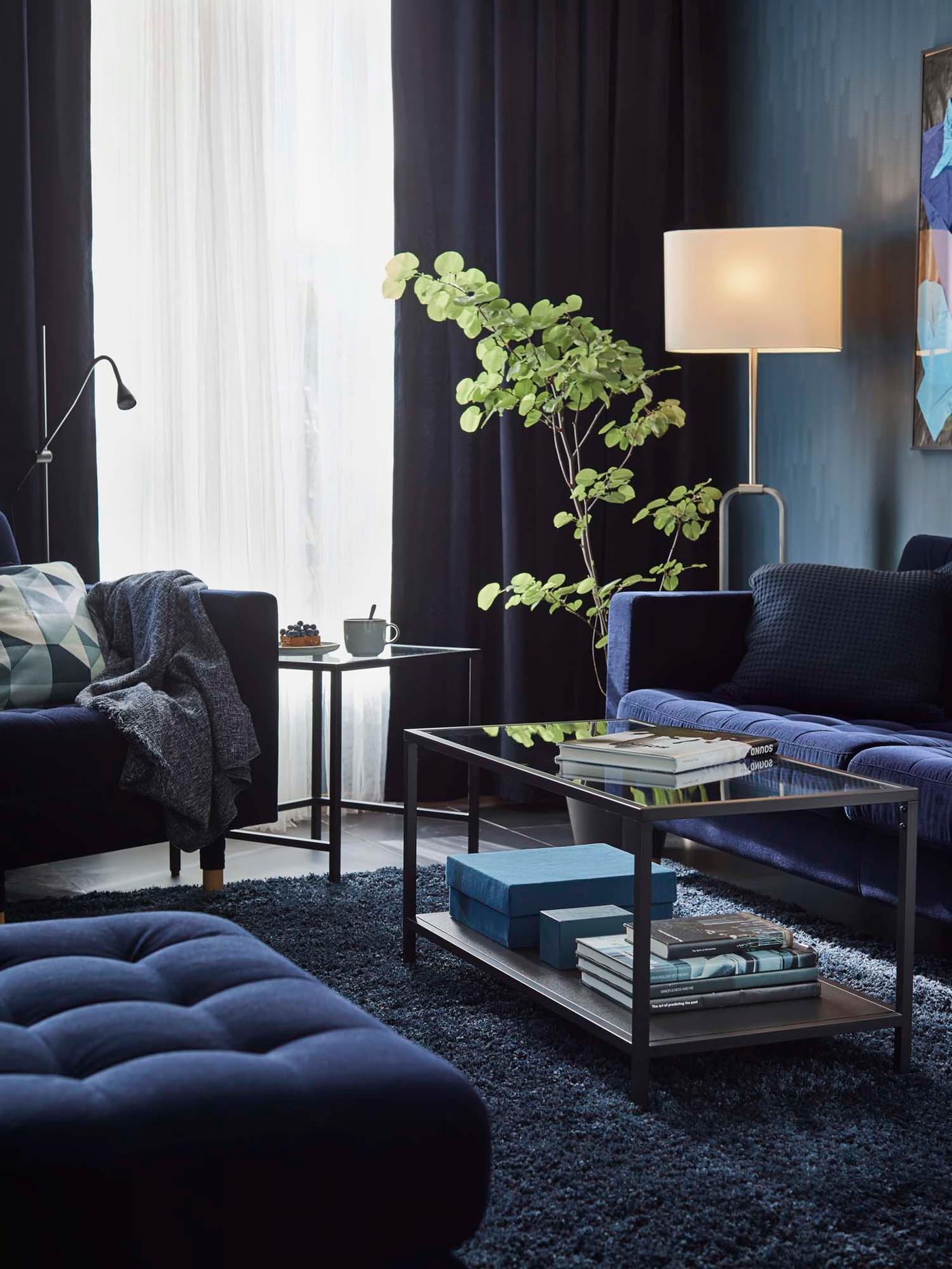A white floor lamp set to a warm glow in the corner of a dark blue living room.