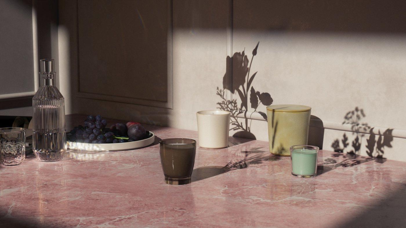 Candle holders standing on a desk together with a fruit bowl.