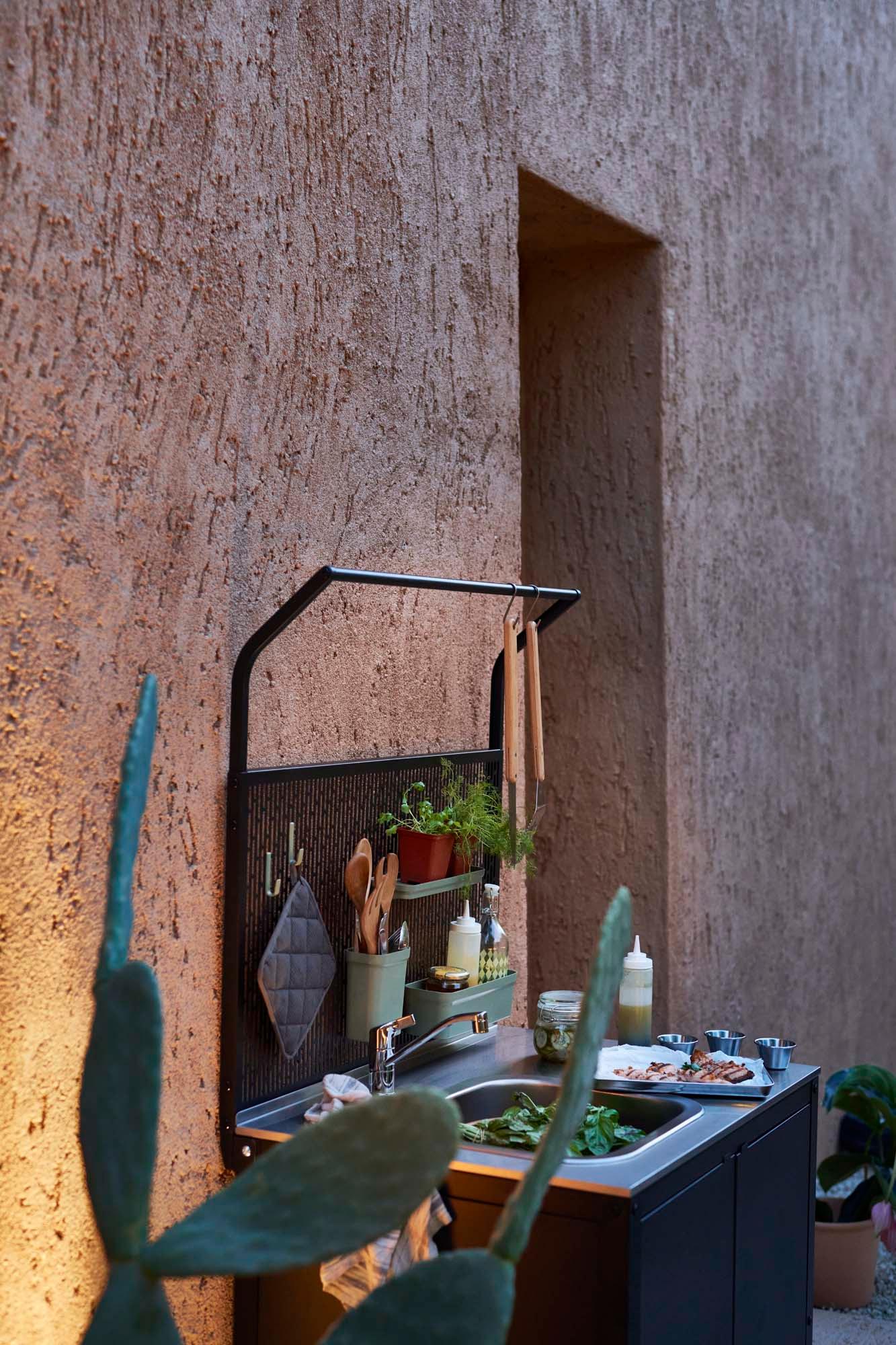 An outdoor area with a black/stainless steel outdoor GRILLSKÄR unit for sink with a GRILLSKÄR back panel attached.