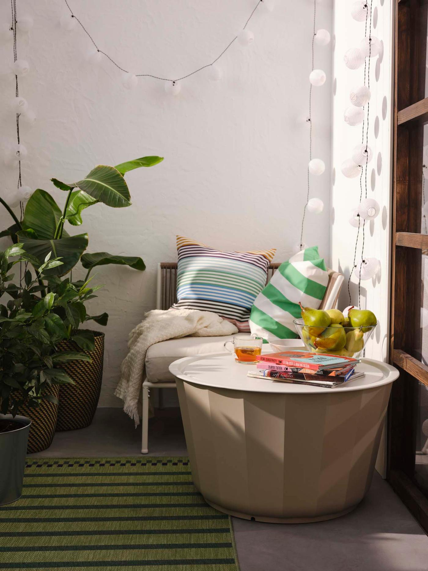 An outdoor area with potted plants, a green striped rug and a LÅGASKÄR coffee table.