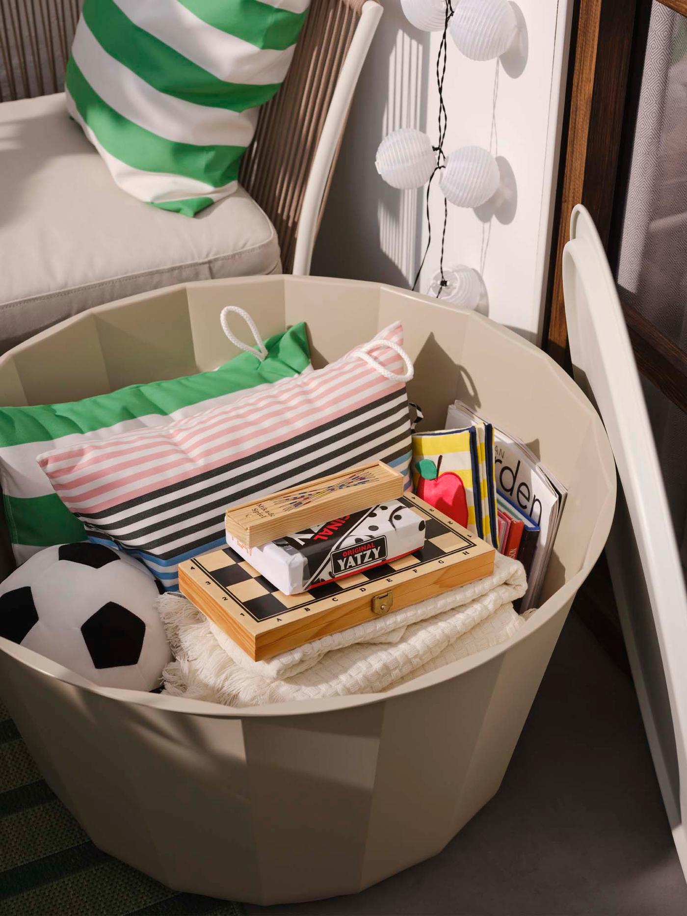 An open LÅGASKÄR coffee table reveals the storage inside filled with games, a ball and cushions.