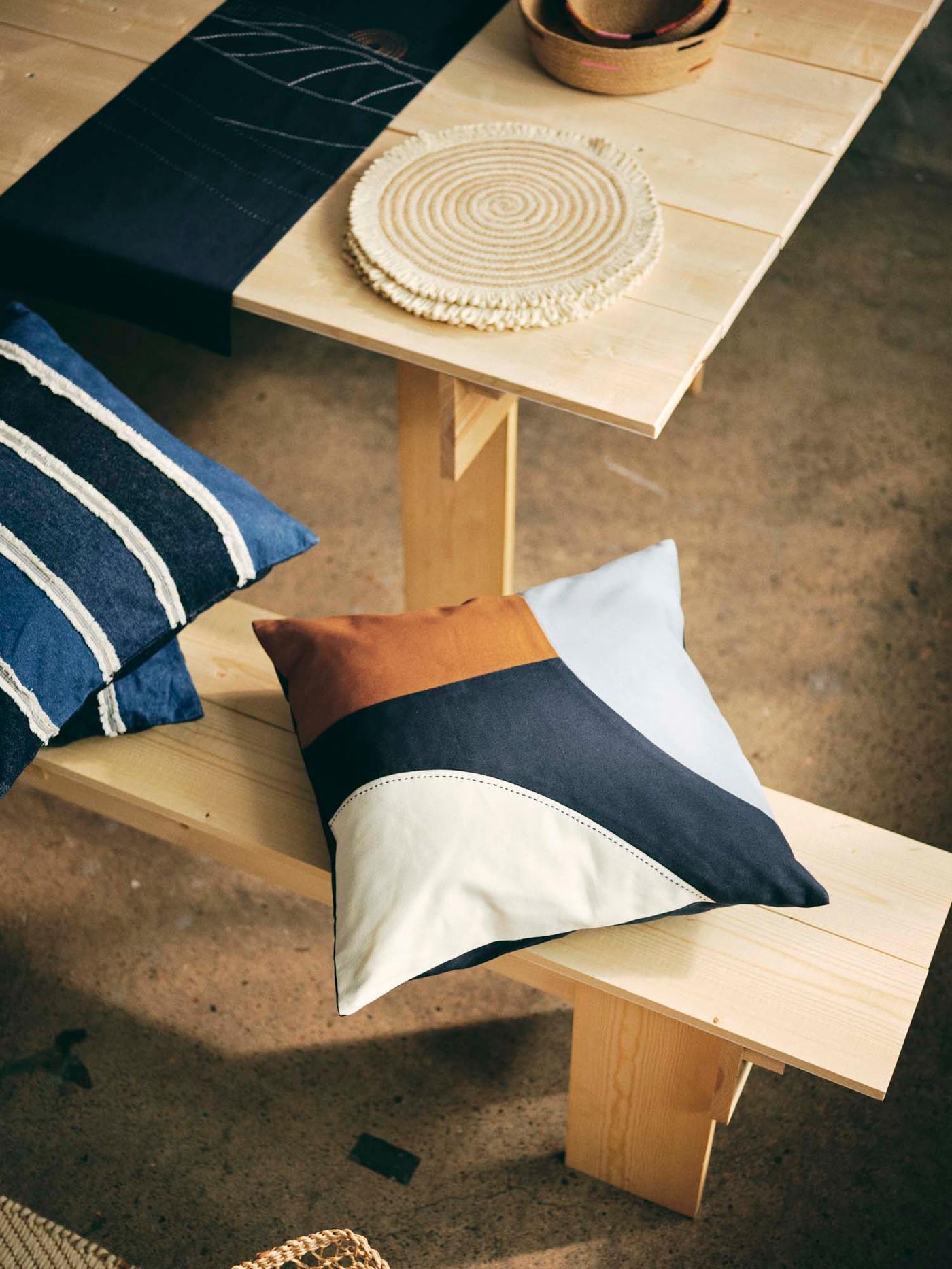 Handmade cushions are placed on a bench, next to a table.