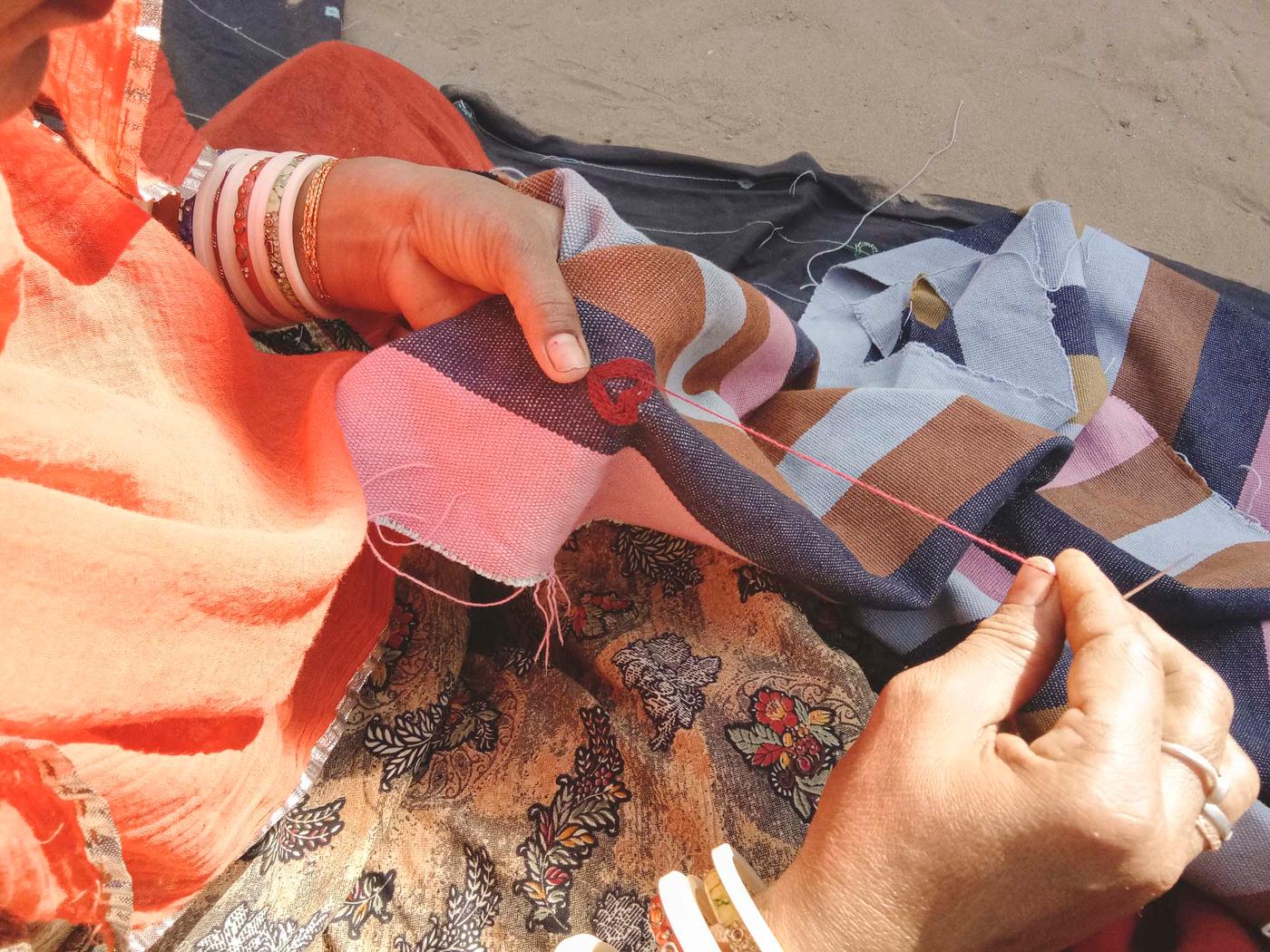 A woman embroiders on a piece of fabric.