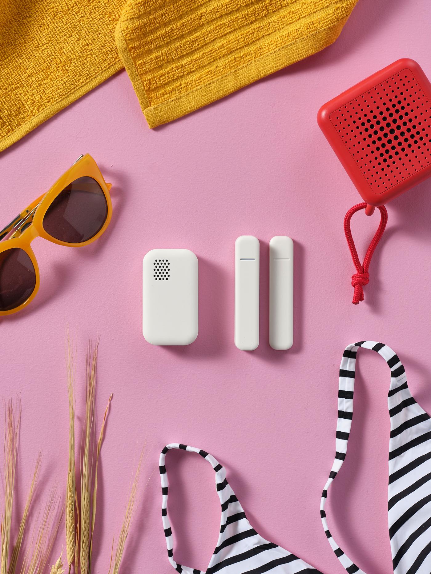 A yellow blanket lies next to a red portable speaker, a striped bikini, yellow glasses and in the middle - three sensors lying next to each other.