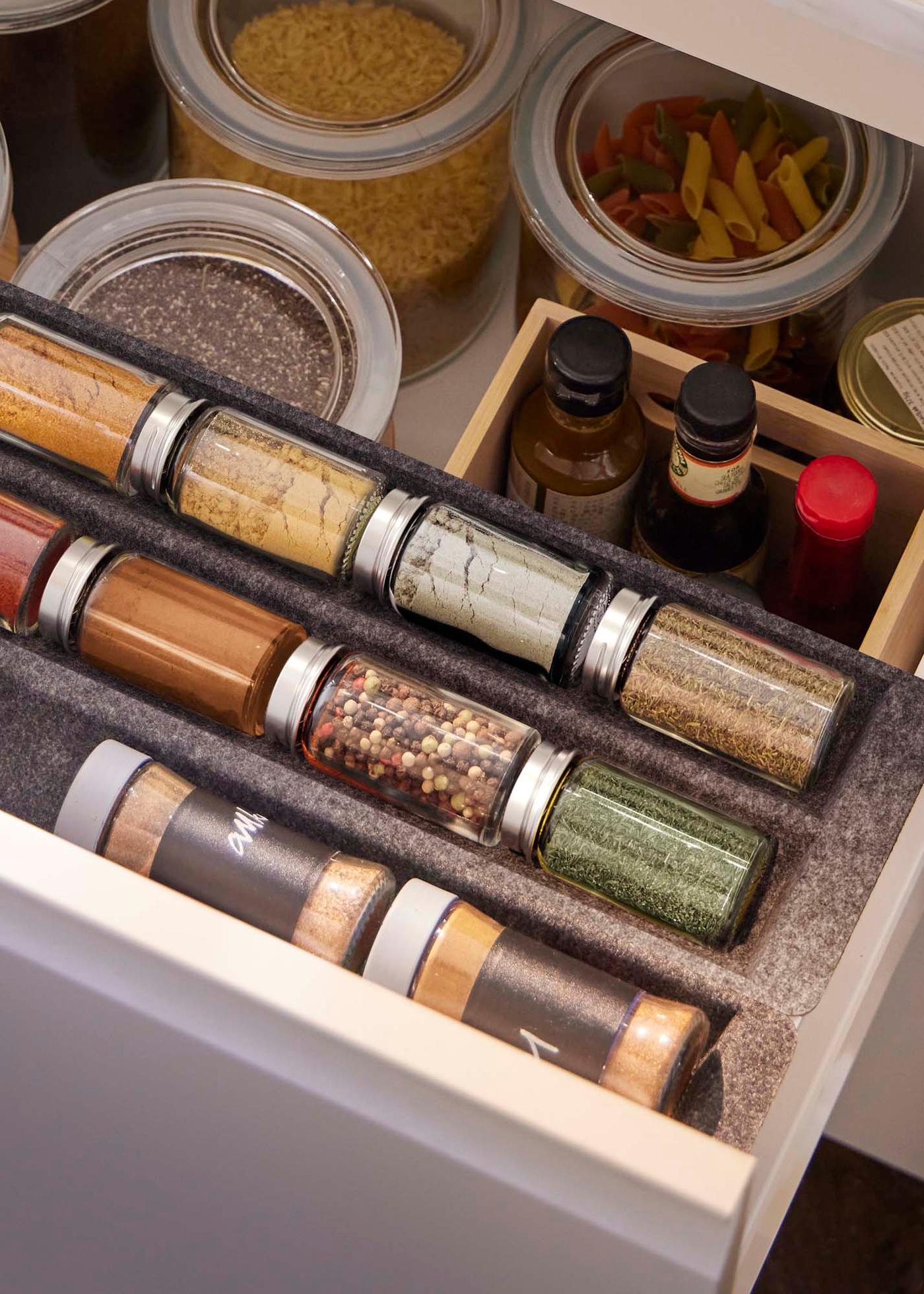 A drawer filled with spice jars. Small jars on top, large ones below.